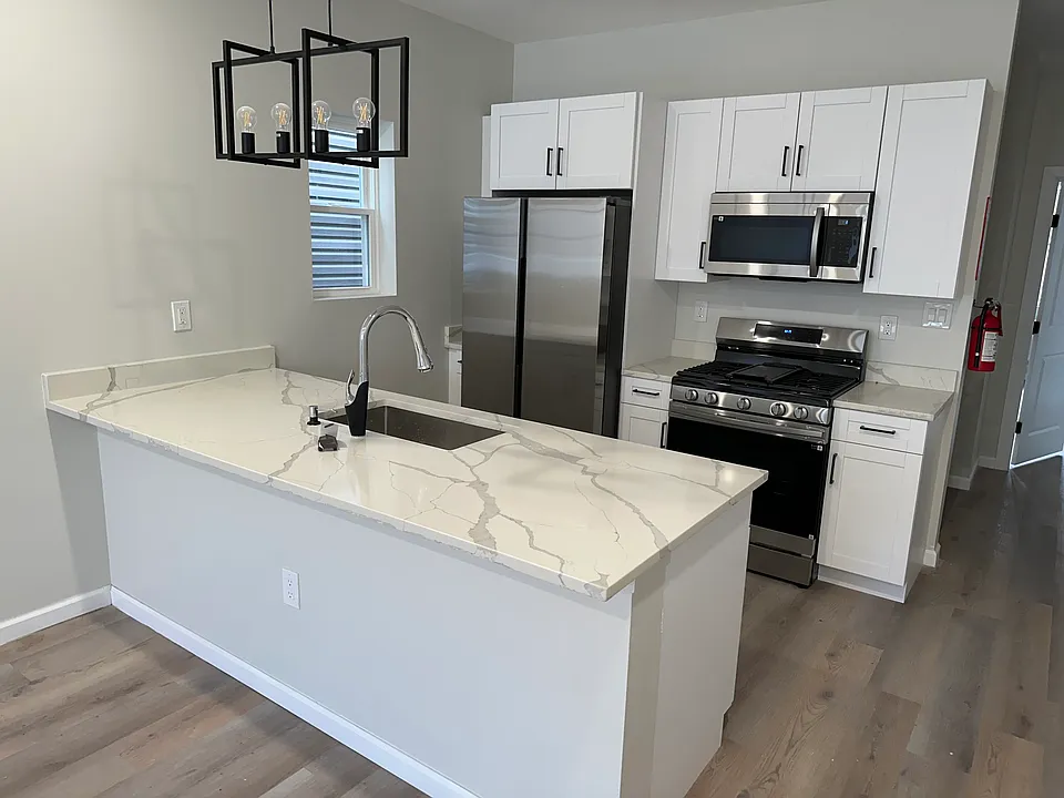 Temple Street kitchen with a white island, pendant light and stainless steel appliances. Temple Street kitchen with a white island, pendant light and stainless steel appliances.